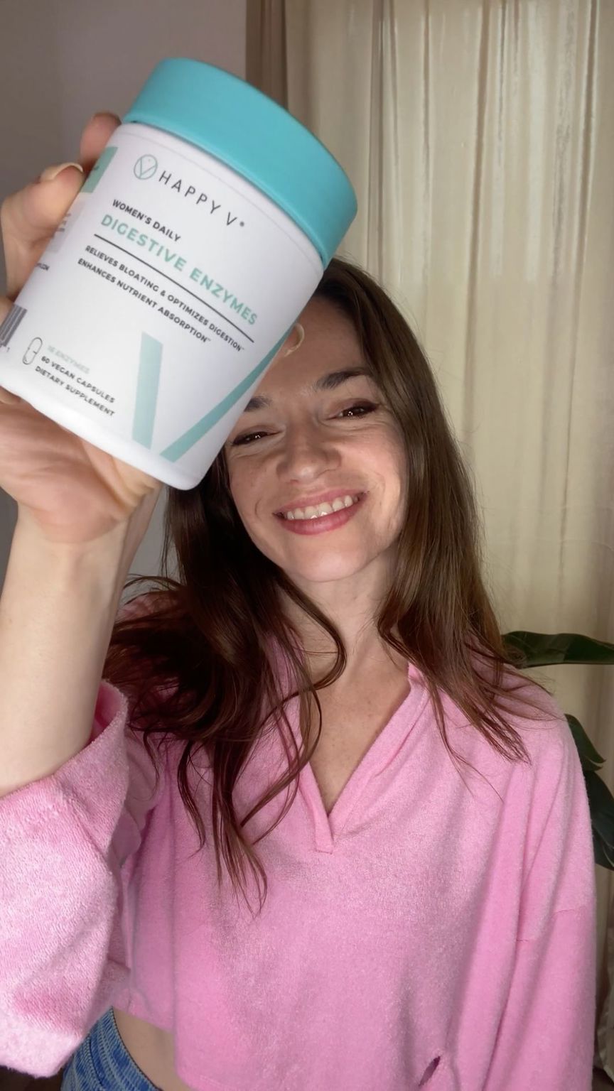 A smiling customer holding a bottle of Happy V Digestive Enzymes