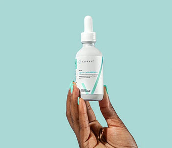 A woman holding a Happy V Liquid Chlorophyll bottle in the air.