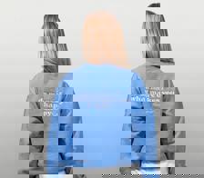 An image showcasing the back of a woman wearing a blue Happy V Crewneck Sweatshirt.