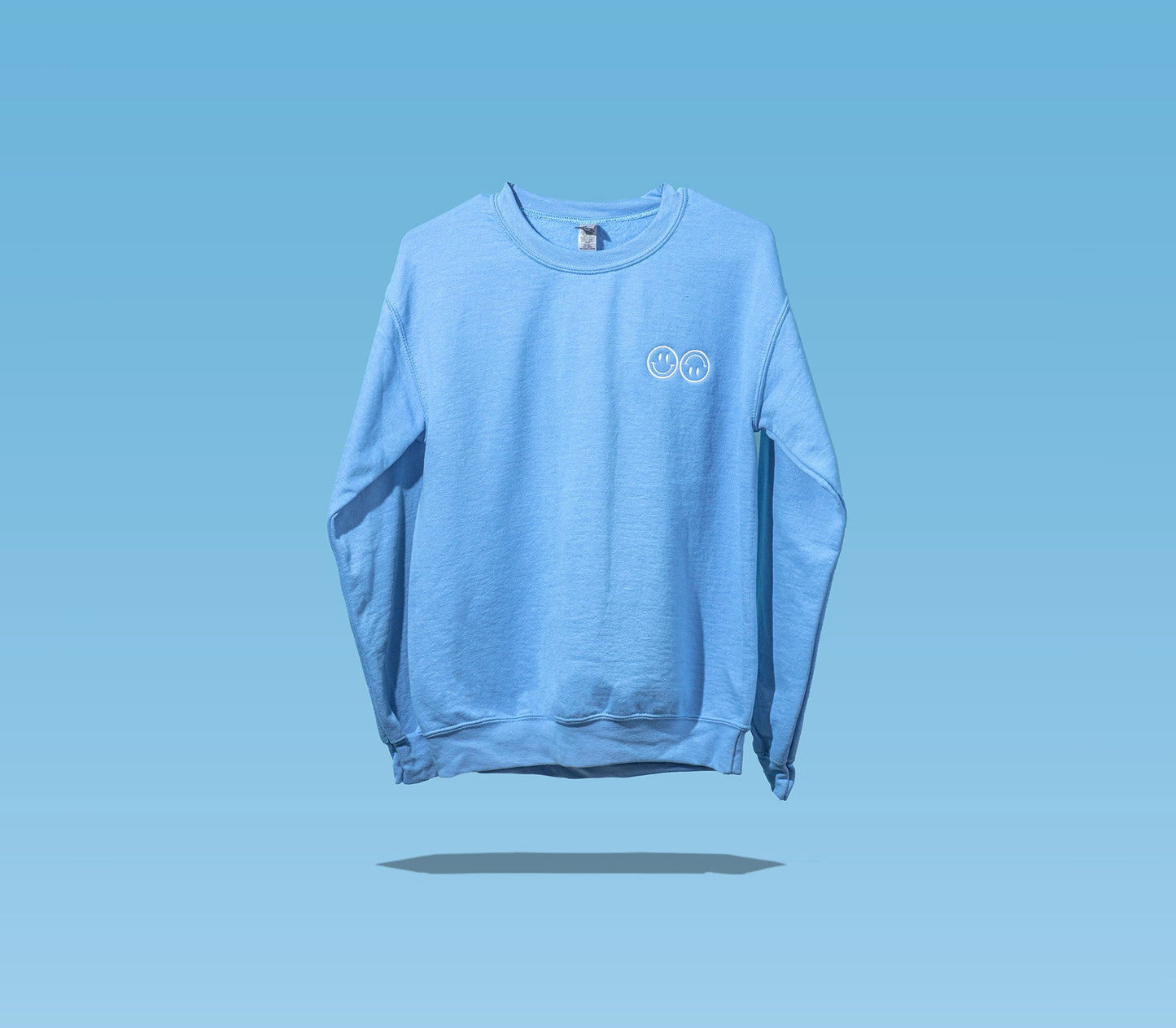 The front side of a Happy V Crewneck Sweatshirt in blue against a blue background.