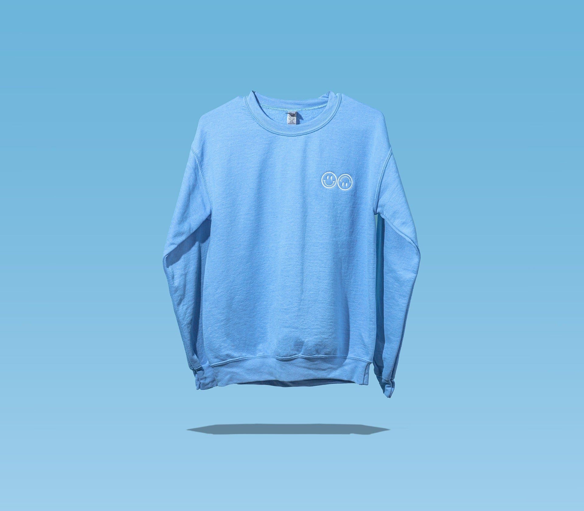 The front side of a Happy V Crewneck Sweatshirt in blue against a blue background.